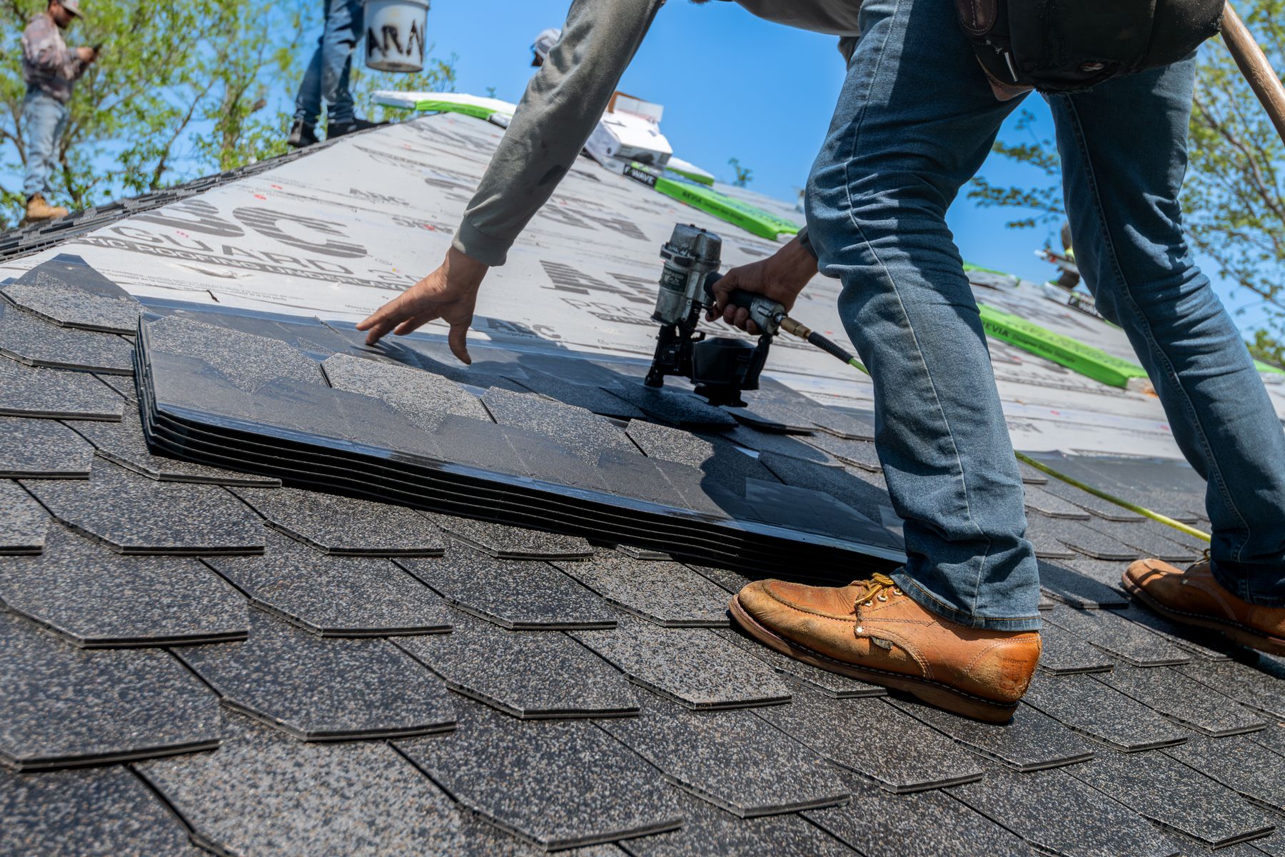 Professional roofers installing shingles on a residential roof